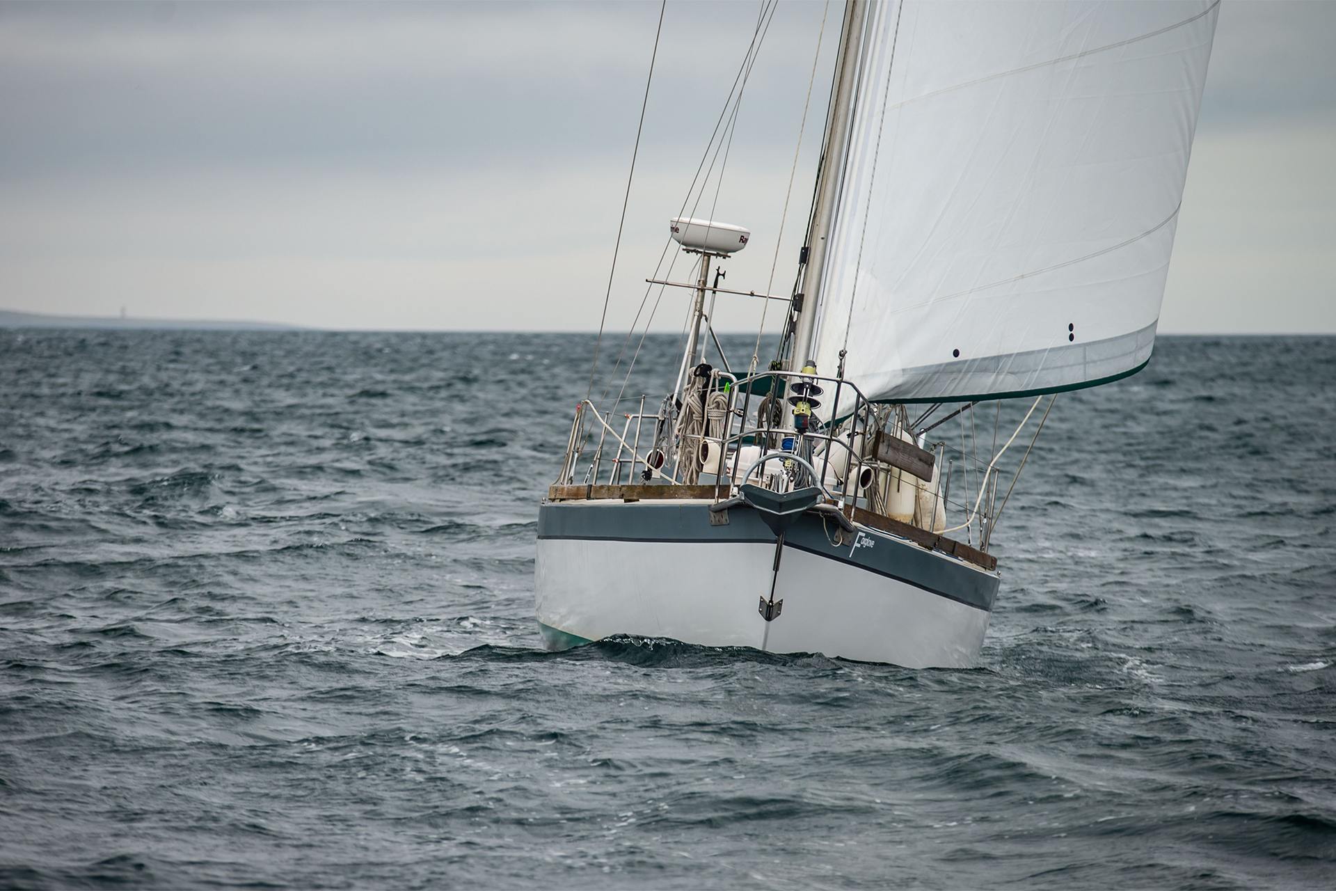 Sailing yacht heeling under a white headsail on a grey, choppy sea