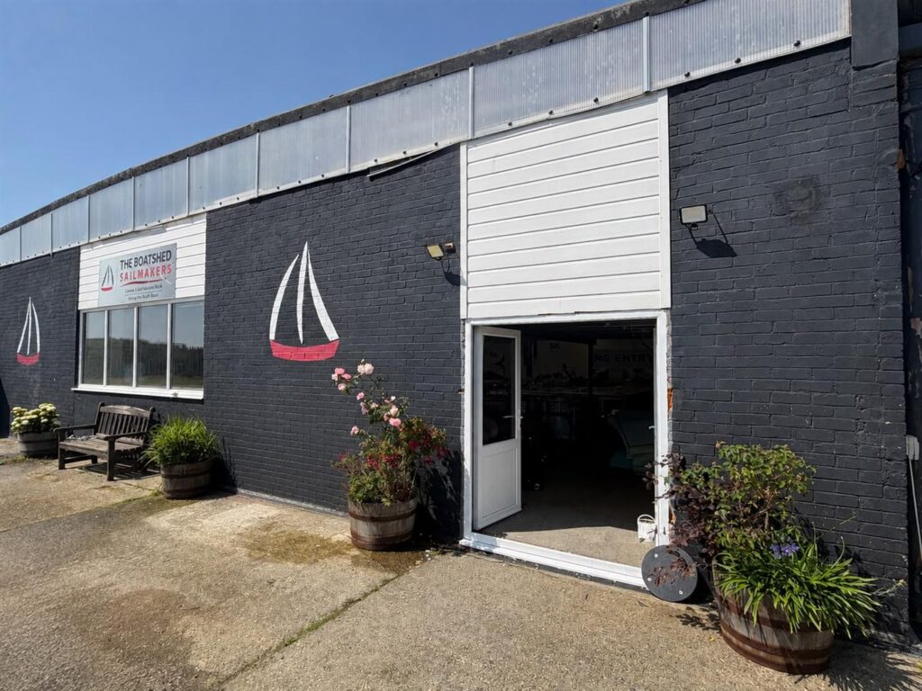 The Boatshed Sailmakers loft on the outer harbour in Pwllheli, with the boat logo painted on its dark brick wall