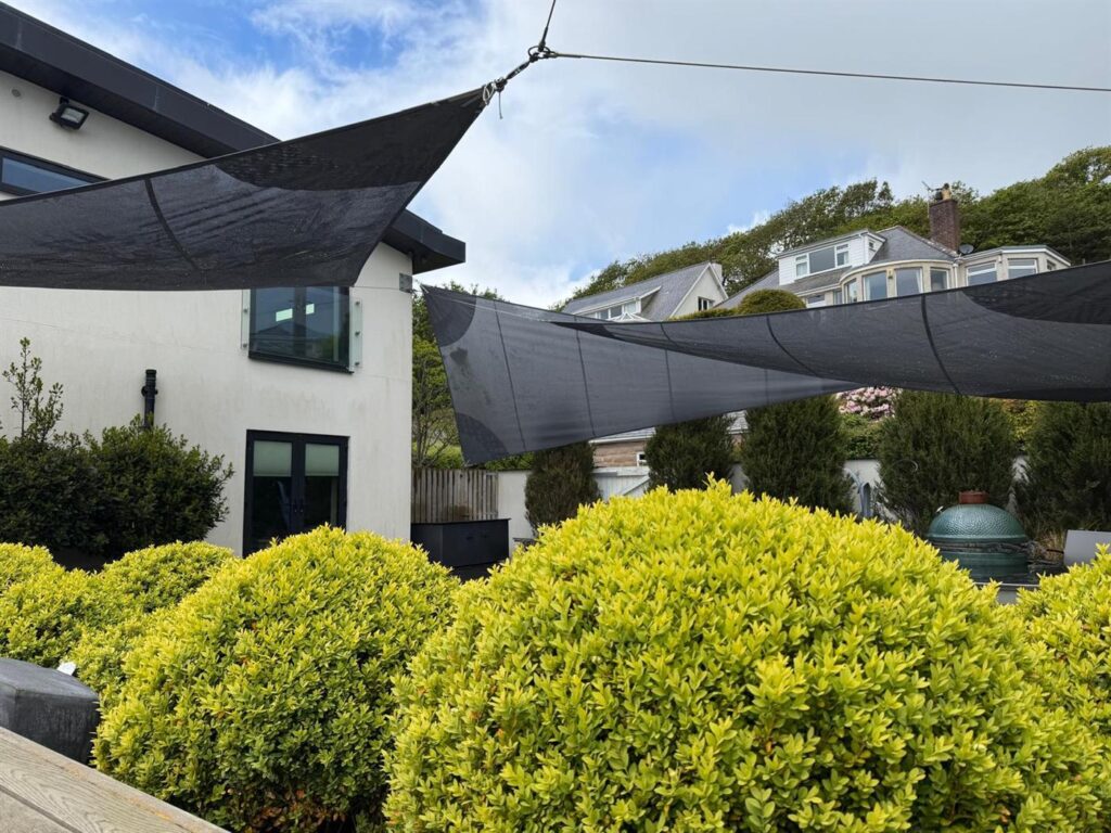 Black shade sails made by Boatshed Sailmakers, rigged over a garden terrace