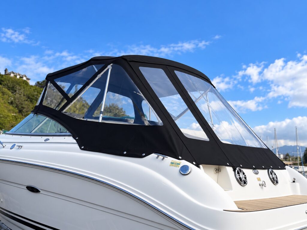 Black canvas cockpit enclosure with large clear windows fitted over the cockpit of a white motor cruiser
