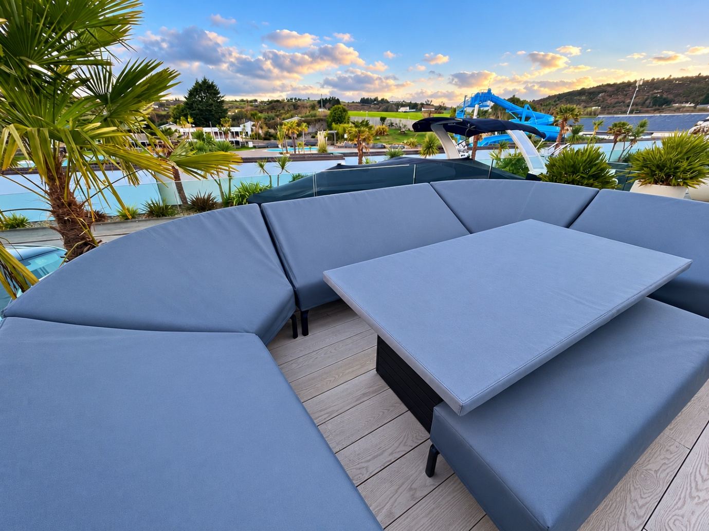 Fitted grey made-to-measure covers on a curved outdoor sofa and dining table on a sunny roof terrace