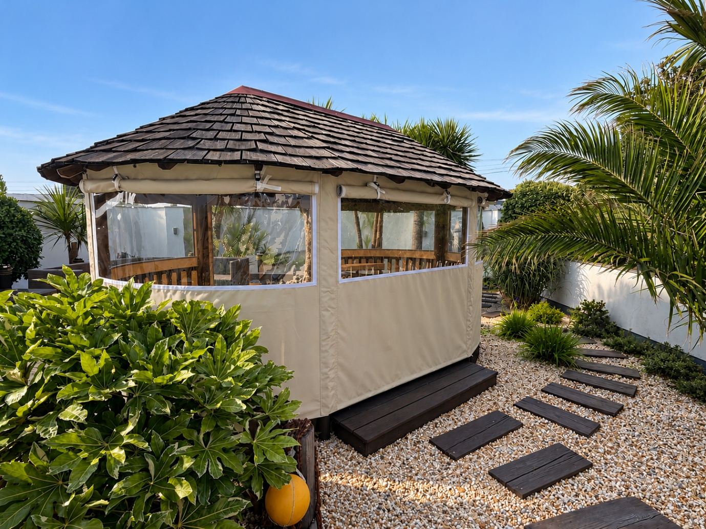 Cream canvas side panels with clear roll-up windows fitted around a wooden gazebo in a garden