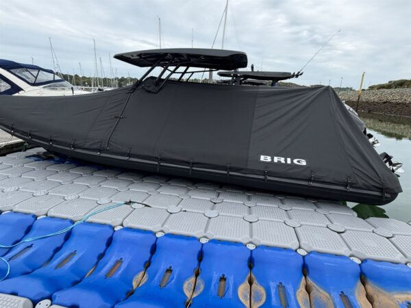Side view of a Brig Eagle 8 with a black full winter cover fitted, on a floating pontoon