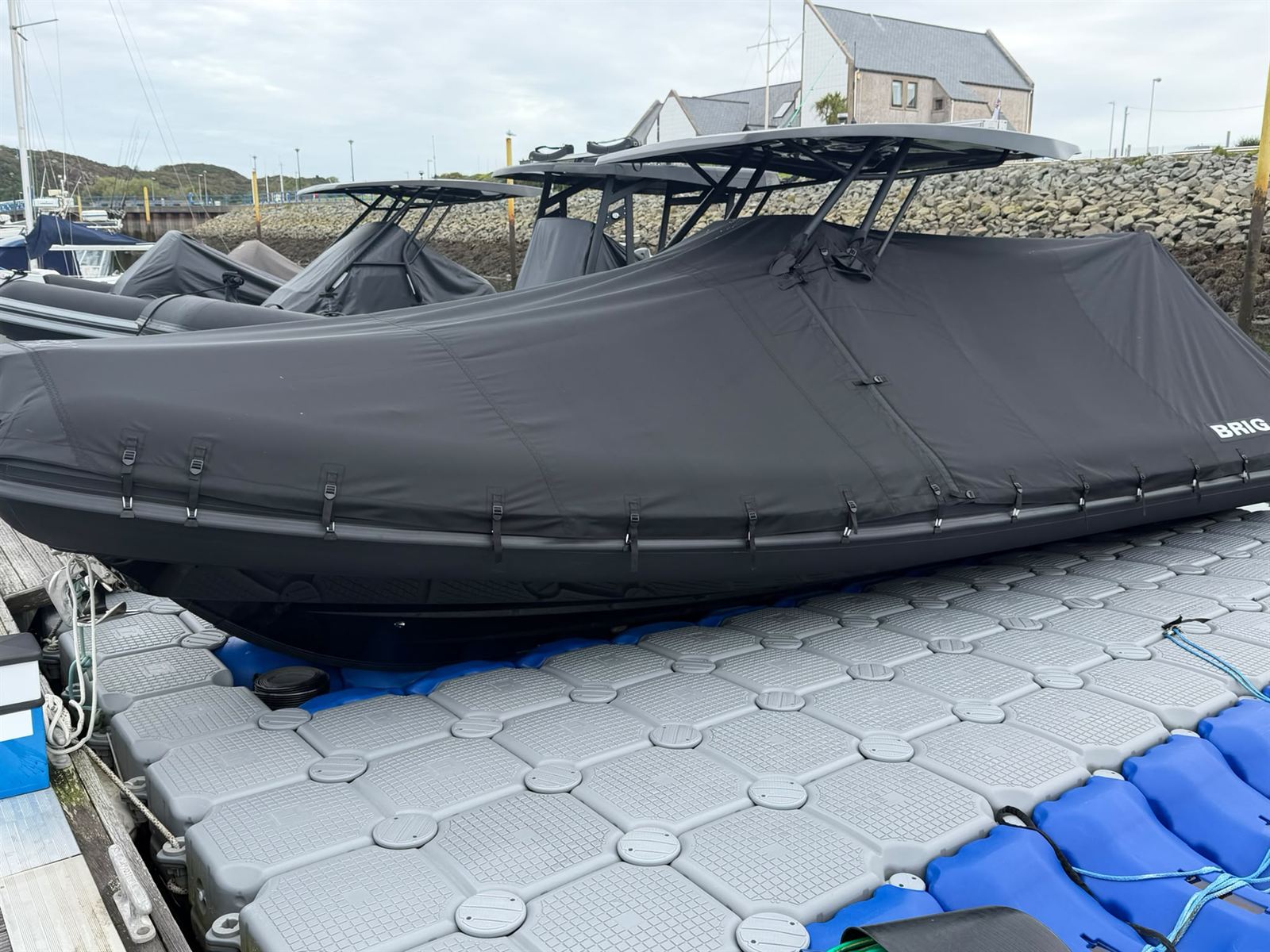 Brig RIB with a black full winter cover fitted around the T-top, moored on a floating pontoon