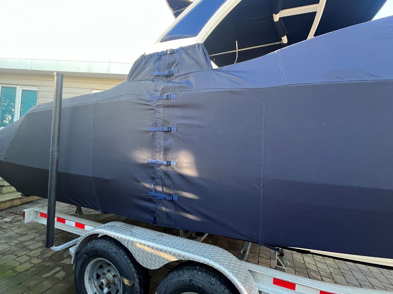 Chaparral 267 Full Winter Cover 2 Side of the navy Chaparral 267 winter cover, showing the buckled straps and the fit around the tower leg